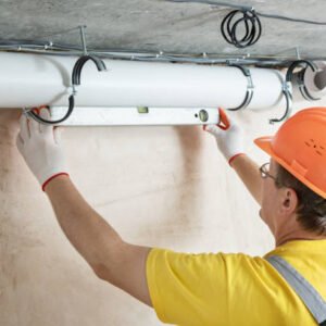 The worker is installing a ventilation system in the apartment.